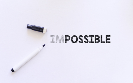 eraser on white paper erase letters "IM" from the word IMPOSSIBLE into POSSIBLEの写真素材