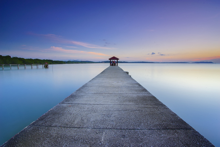Long fisherman jetty heading to the sea with soft pastel sunset at backgroundの写真素材