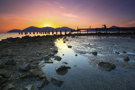 A silhouette of photographer taking a picture of abandoned fisherman during beautiful sunset.の写真素材
