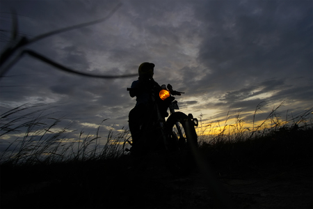 Silhouette of a man riding his motorcycle during sunsetの写真素材