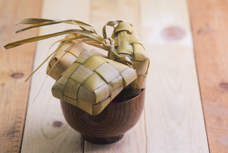 Ketupat (Rice Dumpling) and curry On wooden Background. Ketupat is a natural rice casing made from young coconut leaves for cooking rice during eid Mubarakの写真素材
