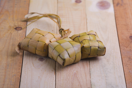 Ketupat (Rice Dumpling) and curry On wooden Background. Ketupat is a natural rice casing made from young coconut leaves for cooking rice during eid Mubarakの写真素材