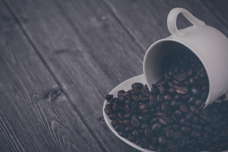 Roasted premium coffee bean in a white cup on black  and woodenの写真素材
