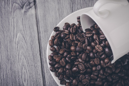 Roasted premium coffee bean in a white cup on black  and woodenの写真素材