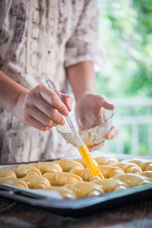 Hand of woman covering croissants with yolkの写真素材