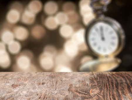 Holiday background, new year clock and bokeh lights with empty wooden table for display productの写真素材