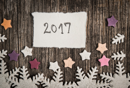 White snowflakes and colorful stars on the wooden background and Happy New Year 2017の写真素材