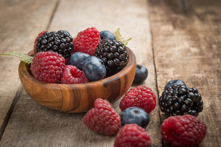Blueberries and raspberries bowl on wooden tableの写真素材
