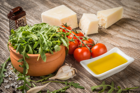 Arugula, tomatoes,cheese and oil on rustic tableの写真素材