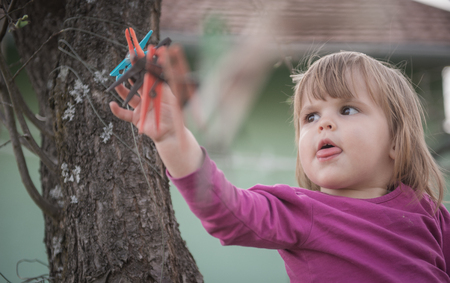 Little girl reaching for clothespinの写真素材