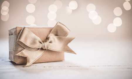 Gift box with satin gold ribbon and blurred backgroundの写真素材