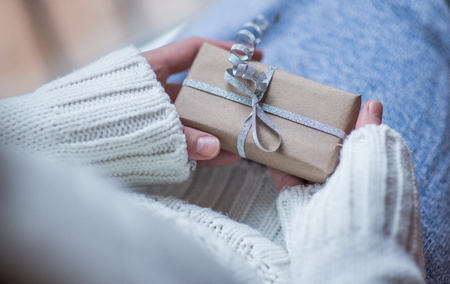 Female hands holding present with silver bowの写真素材