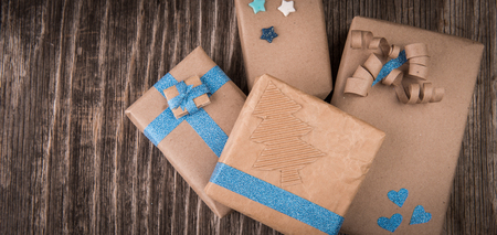 Brown cardboard box with blue and golden bow and ribbon on rustic wooden backgroundの写真素材