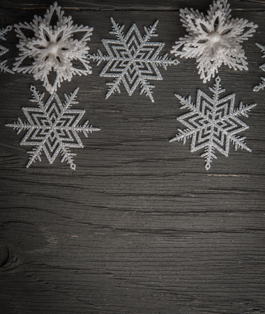 Snowflakes and stars over black wood with space for textの写真素材