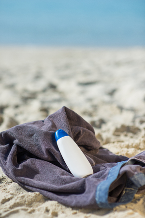 Bottle of sunscreen on beach towel on sandの写真素材