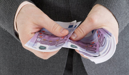 stack banknotes of 500 euro in male hands on a gray backgroundの写真素材