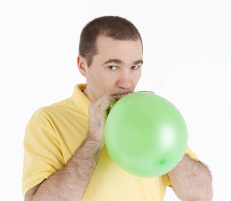 man inflates a green ball on a light backgroundの写真素材