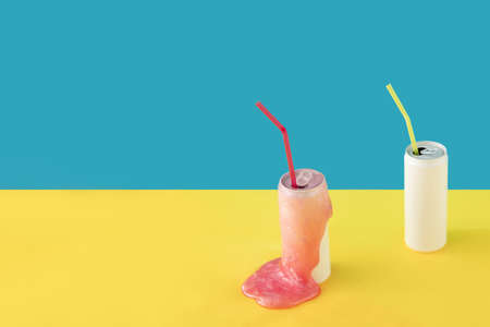 Two cans with straws and a slime on a yellow-blue background with copy. Surrealism and retrofuturism in retro colors. Minimal vintage conceptの写真素材