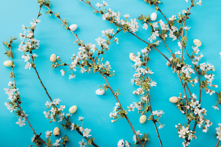 Easter layout with cherry blossom branches and quail eggs on blue background. Minimal Easter...