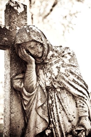 statue of a sorrowful woman beside a crossの写真素材