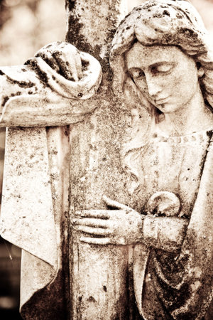 statue of a woman holding a cross in sepiaの写真素材