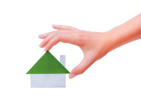 Green paper house in a hand on a white backgroundの写真素材