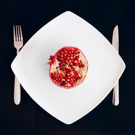 Pomegranate fruit healthy eating in a plate on a black backgroundの写真素材