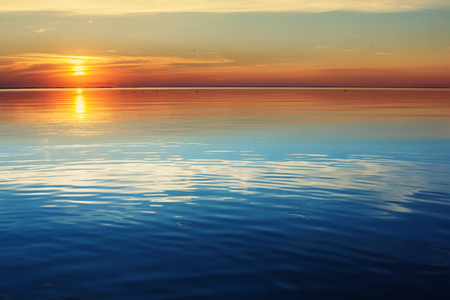 Lake tranquil sunset landscape above water wavesの写真素材