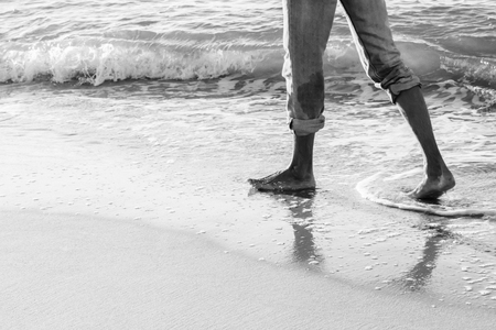 Adult man walking on he sea wave sand sunrice beach black and whiteの写真素材