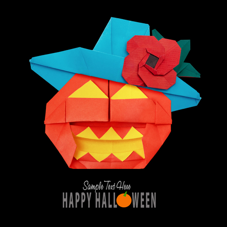 Origami funny Halloween pumpkin with black hat isolated on black backgroundの写真素材