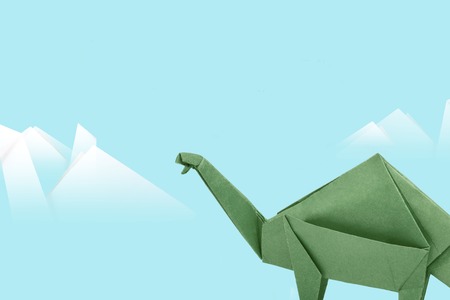 Isolated origami paper green dinosaur on blue mountain backgroundの写真素材