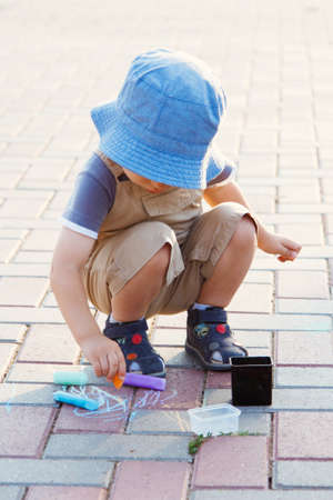 Little boy drawing with chalk on pavement outdoodの写真素材