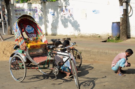 DHAKA, BANGLADESH - NOVEMBER 2: Driver of a rickshaw squats on the street, Rickshaw empty on November 2, 2014 in Dhaka, Bangladeshのeditorial素材