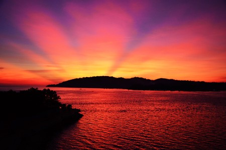 The sun setting behind it a hill in Kota Kinabalu, Malaysia, Borneo, incredibly red skyの写真素材