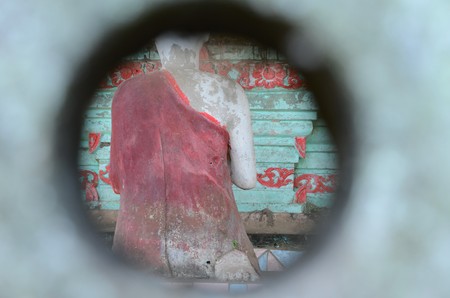 Shot through a little hole, praying Buddha statue from behindの写真素材