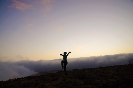 Silhouette of a woman doing the crane pose on top of a mountain over the clouds in Omanの写真素材
