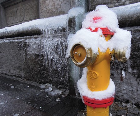 Red and yellow fire hydrant in Reykjavik covered in snow and iceの写真素材