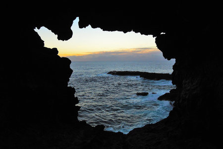 View onto the ocean during sunset through one of the windows at the Ana Kakenga Cave or two windows...