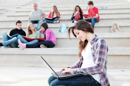 students working with laptops and books on campusの写真素材
