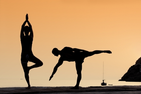 healthy couple doing yoga exercises outdoorsの写真素材