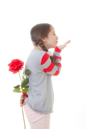 girl child with flower gift and blowing kiss  for valentines or mothers dayの写真素材
