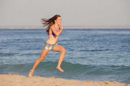 fit healthy young woman running on beachの写真素材