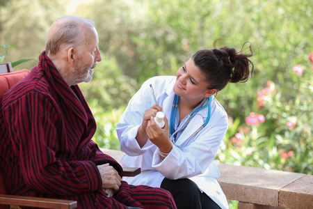 smiling Dr or nurse giving medication to senior patient. の写真素材