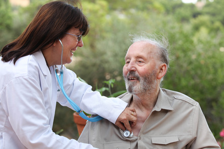 dr with stethoscope checking senior patients heat beatの写真素材