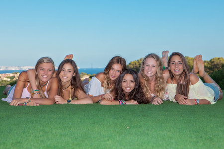 group of happy healthy teen girls smiling laying on grassの写真素材