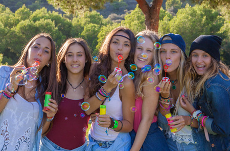 group of kids blowing bubbles having funの写真素材