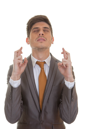 business man fingers crossed eyes closed in hope and optimismの写真素材