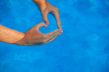 summer vacation love heart shaped hands in pool.の写真素材