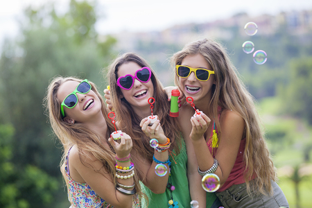 happy smiling gropu of teen girls blowing bubbles