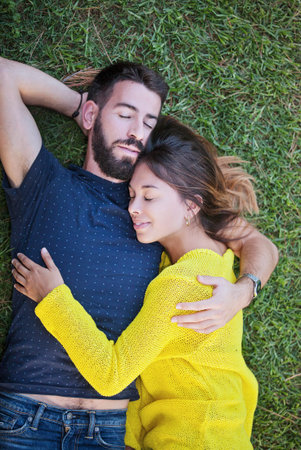 happy couple in love laying on grass in summer